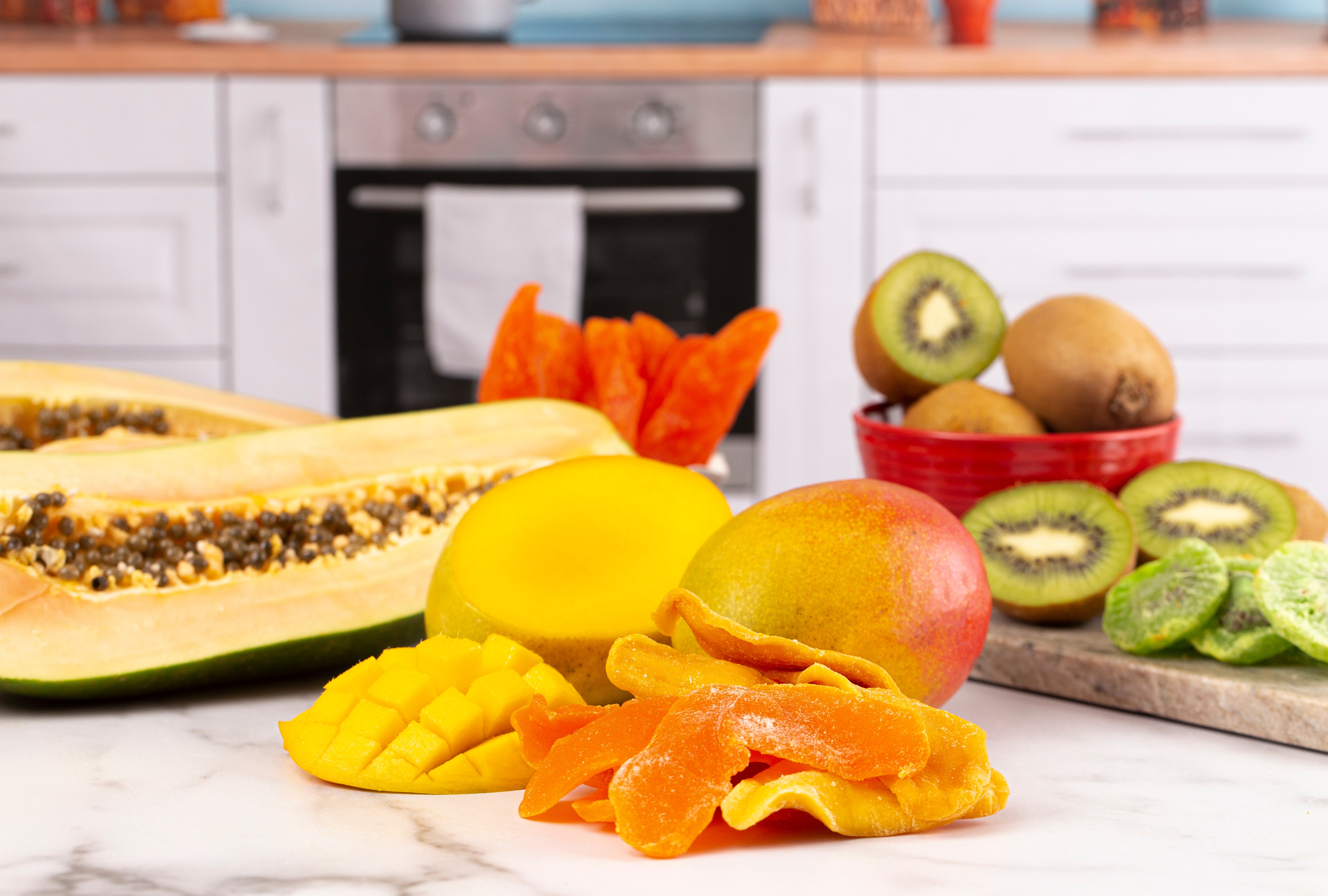 Fontes naturais de enzimas digestivas, como mamão, manga e kiwi, em um balcão de cozinha.